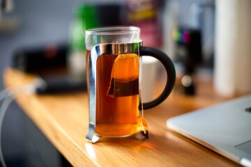 cup of fresh tea bag on wooden desk. blurry back ground