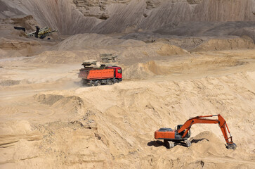 Dump truck transports sand in open pit mine. Excavator on the development of sand in a quarry. Mining industry concept