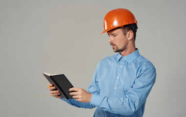 civil engineer in orange hard hat holding documents in hands notepad business work