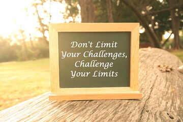 Inspiration and creative concept: Blackboard written " A Don't Limit Your Challenges, Challenge Your Limits " at outdoor with natural lights, selective focus