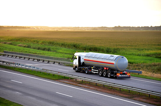 Tank truck driving on highway. Transportation of liquid goods. Metal chrome cistern tanker with petrochemicals products. Oil and Gas logistics. Out of focus, possible granularity, motion blur
