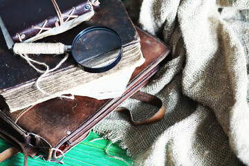 Old leather bag with a magnifying glass on a brown traveler wooden table background with copy space.
