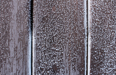 Background from wooden vertical brown boards covered with snowflakes