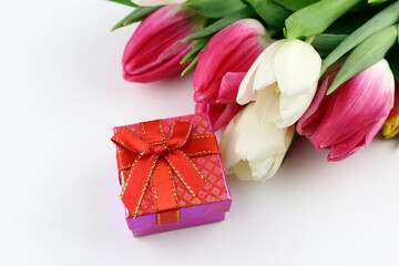 Red small gift box with a bow with tulips on a white background. Gifts for a woman