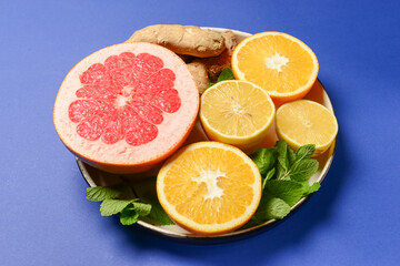 Colorful cirtus slices over blue background. Cut lemons and grapefruit with ginger on a plate.