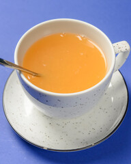 Cup of ginger citrus tea over blue background. Tea time concept.