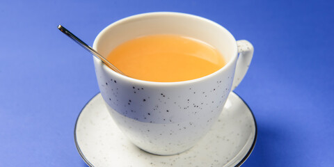 Cup of ginger citrus tea over blue background. Tea time concept.