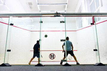 Squash player in action reaching on squash court. Out of focus