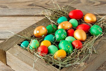 Colorful hand painted easter eggs in white wooden box on wooden table with copy space.