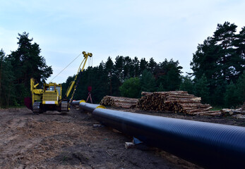 Natural gas pipeline construction work in forest area.  Petrochemical Pipe on top of wooden supports. Installation and Construction the Pipeline for transport gas to LNG plant