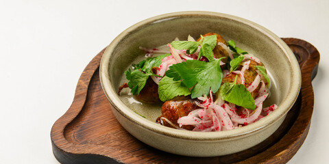 BBQ fiery sausages with vegetables served in a ceramic bowl over white background. Delicious idea for dinner.