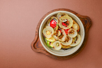 Baked vegetables: mushrooms, zucchini, eggplant served in ceramic bowl over orange background.