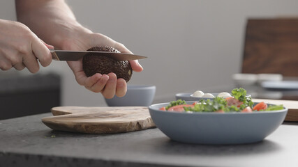 man make salad with kale, mozzarella, avocado and cherry tomatoes, cut avocado