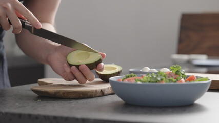 Obraz na płótnie Canvas man make salad with kale, mozzarella, avocado and cherry tomatoes, cut avocado