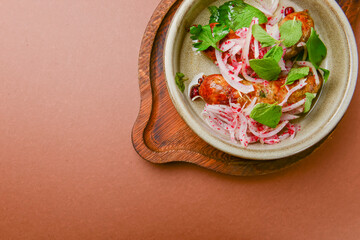 BBQ fiery sausages with vegetables served in a ceramic bowl over brown background. Delicious idea for dinner.