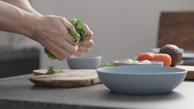 man make salad with kale, mozzarella, avocado and cherry tomatoes, massage kale