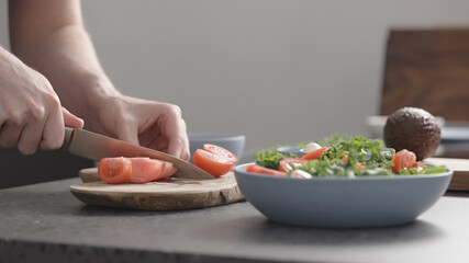 man make salad with kale, mozzarella, avocado and cherry tomatoes, cut cherry tomatoes