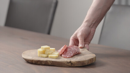 man put olive board with vintage cheese and salam on walnut table