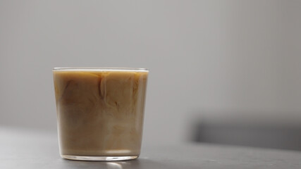 pour milk in coffee in tumbler glass on concrete countertop with copy space