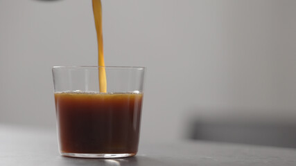 pour coffee in tumbler glass on concrete countertop with copy space