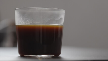 pour water in coffee in tumbler glass on concrete countertop with copy space