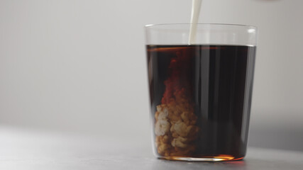 pour cream in cola in tumbler glass on concrete countertop with copy space