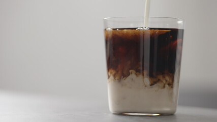 pour cream in cola in tumbler glass on concrete countertop with copy space