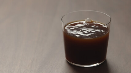 pour coffee in tumbler glass on walnut wood table with copy space