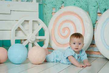 Naklejka premium A baby lies on a soft surface in a bright room, dressed in dark-colored clothing. The concept of childhood