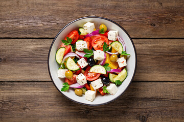 Classic Greek salad with fresh vegetables, feta cheese and  olives. Healthy food. Wooden background. Top view