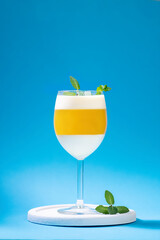 Italian dessert panna cotta with tangerine jelly layer in a glass on blue background