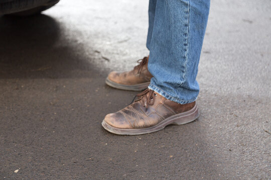 Man's legs in blue denim jeans and brown boots.
