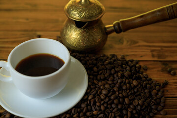 Coffee beans and turkish coffee pot near white cup