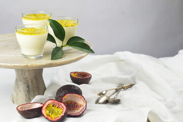 Italian dessert panna cotta in a glass cups with fresh passion fruits on a cake stand.