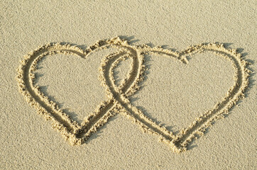 Two entwined hearts drawn in the sand of a beach representing love, valentine, romance.   