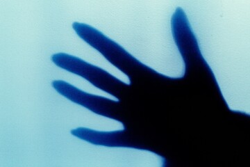 a blurred shadow of a hand on a painted wall, the shadow of a woman's hand