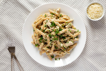 Homemade Chicken Alfredo Penne with Parsley on cloth, top view. Overhead, from above, flat lay.