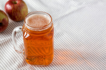 Hard Apple Cider Ale in a Glass Jar Mug on cloth, low angle view. Space for text.