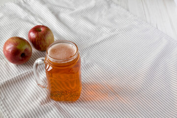 Hard Apple Cider Ale in a Glass Jar Mug on cloth, side view. Copy space.