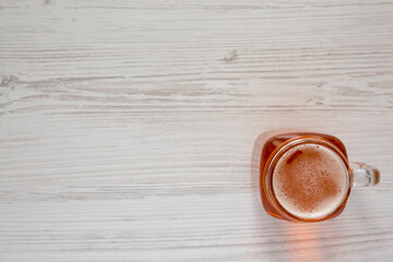 Hard Apple Cider Ale in a Glass Jar Mug on a white wooden table, top view. Flat lay, overhead, from above. Copy space.