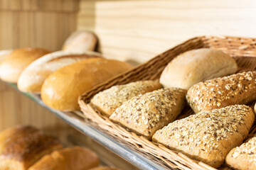 A freshly baked triangular-shaped bun with various seeds is on the shelf of a bakery store.