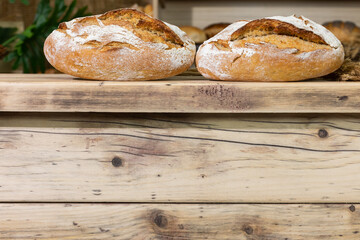 Two loaves of well-baked, cracked bread lie on the wooden counter. Traditional bakery.