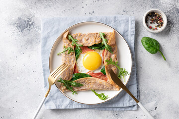 buckwheat crepe galette with egg, ham and spinach on gray background. Healthy food concept. top view. copy space