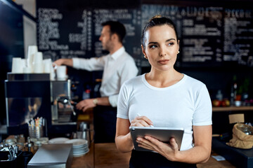 Female barista small business owner using digital tablet in cafe