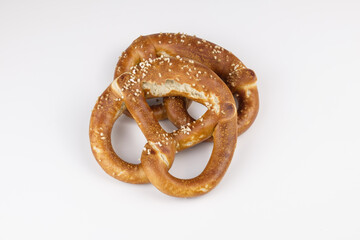 Zwei knusprig braune Brezeln mit Salz (Laugengebäck) liegen auf einem neutralen weißen Hintergrund