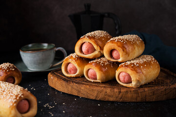 Homemade sausages in dough on a wooden board, dark background