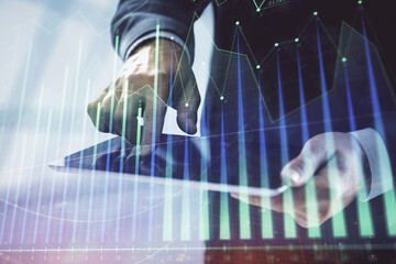 Obraz premium Double exposure of man's hands holding and using a digital device and forex graph drawing. Financial market concept.