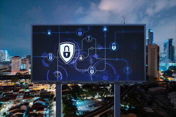 Padlock icon hologram on road billboard over panorama city view of Kuala Lumpur at night to protect business, Malaysia, Asia. The concept of information security shields.