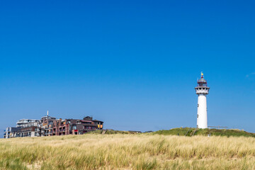 Fototapeta na wymiar Lighthouse in the dunes against a bright blue sky. Coastal town Egmond aan Zee in the Netherlands. 