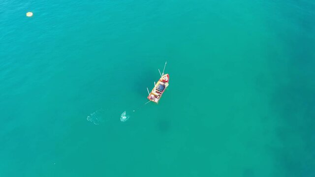 Aerial view drone flying top view above on fishermans on the long tail boat lay a fishing net in the sea. Footage b roll 4k aerial view of fishermans
